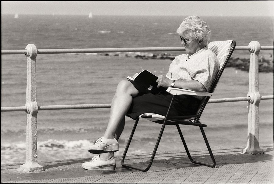 Woman reading in a deck chair beside a seaside railing