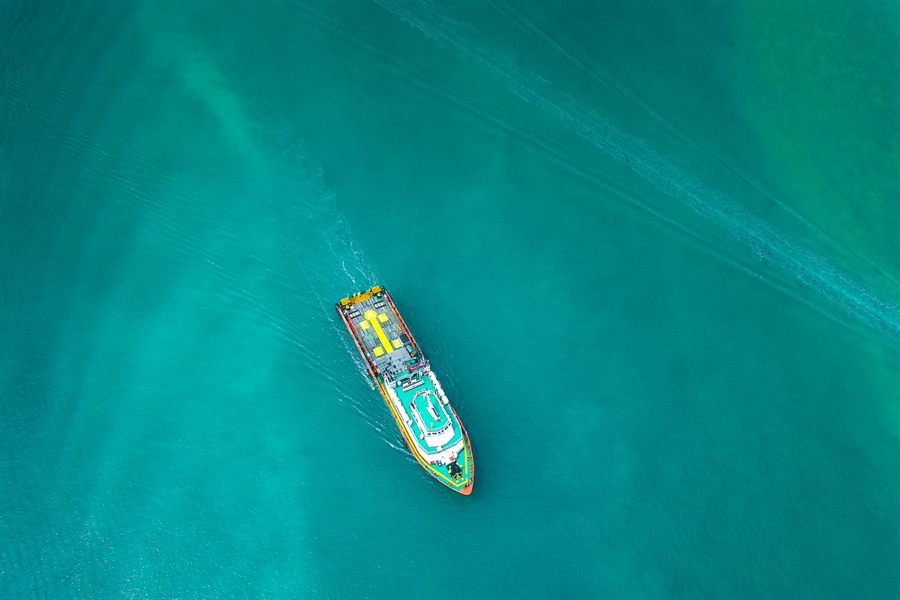 Ship crossing turquoise water seen from above