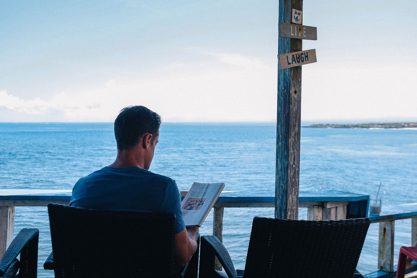 Man reading at a seaside table, like the cruise experts whose reviews travelers rely on