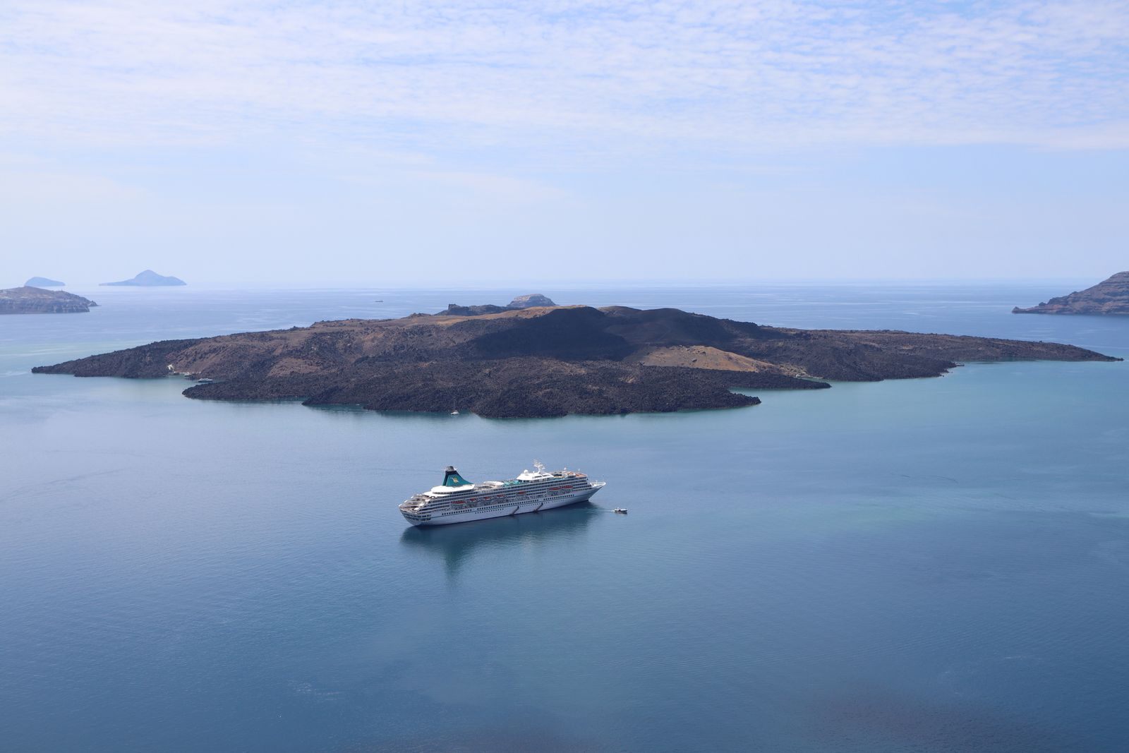 Cruise ship anchored off a volcanic island, the kind of voyage behind cruise ship ratings 2026